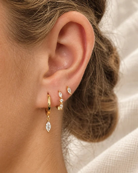 Gold hoop and drop earrings worn on an ear